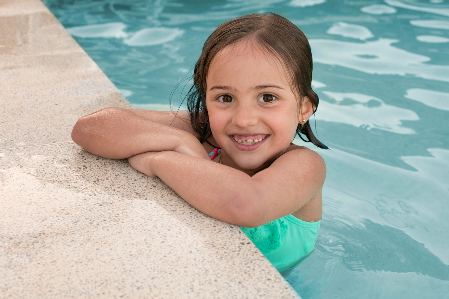 Smiling girl at the side of a swimming pool