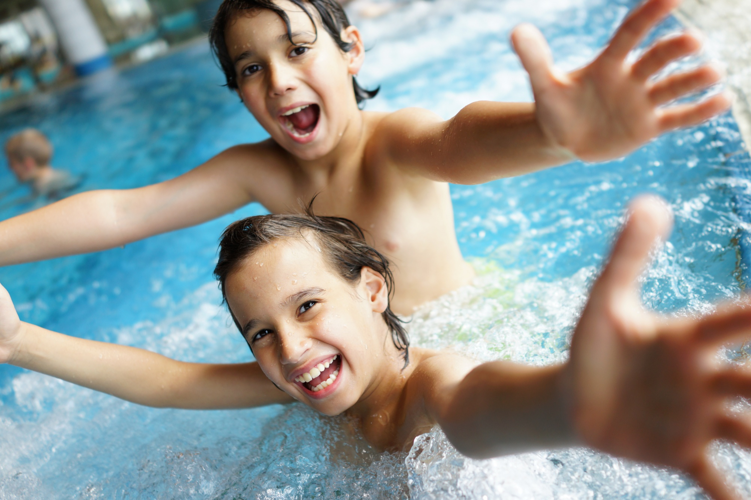 Children splashing happily in a sunny outdoor pool