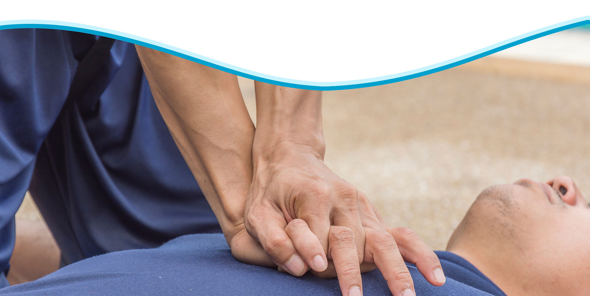 A First Aid instructor guiding a student practising CPR chest compressions