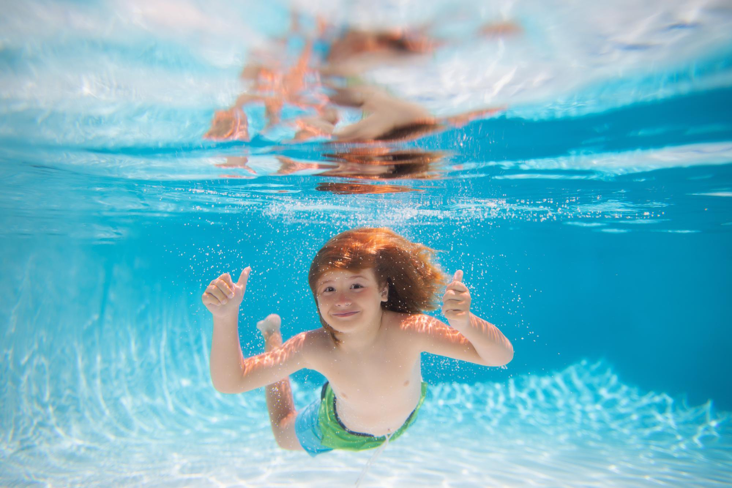 Child swimming underwater in a clear blue pool